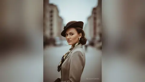 Elegant woman in a vintage beige blazer and brown wide-brimmed hat posing on a soft-focus city street.
