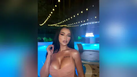 NicoleBella poses outdoors at night wearing a peach-colored bustier top with long dark hair falling over her shoulders.