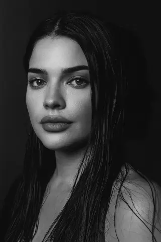 Close-up black and white portrait of a beautiful woman with wet hair and a moody, intense expression.