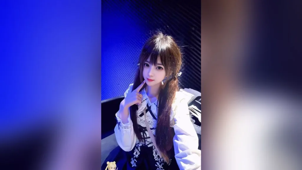 YiQiao — YiQiao poses in a white and black gothic lolita outfit with long brown hair against a blue background.