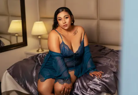 Beautiful woman in blue lace lingerie sitting on a bed in a cozy, dimly lit bedroom.