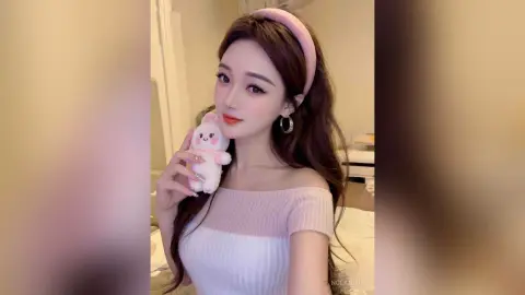 Young woman in a white off-the-shoulder top and pink headband holding a cute plush bunny in a cozy room.