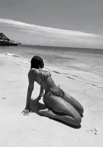 Woman in zebra print bikini relaxing on a sunny tropical beach sand.