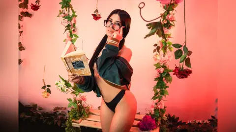 Young woman in dark green top reading a book amidst pink roses in a romantic, dreamy setting.