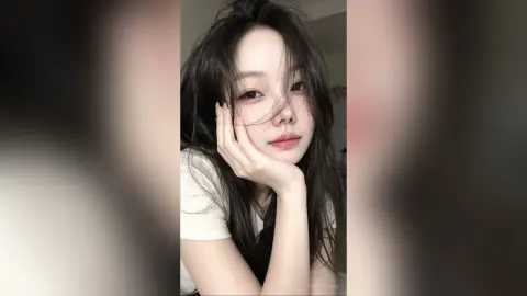 Young woman with long dark hair in a white t-shirt posing for a soft, dreamy close-up portrait.