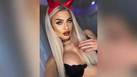 Blonde woman in black lace outfit and red devil horns posing with a glamorous makeup look.