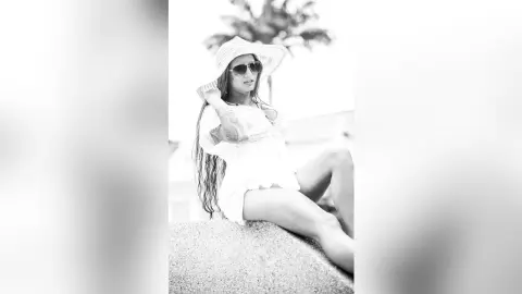 AndreaKalo wearing a white hat and sunglasses, posing outdoors with her long hair down and legs visible.
