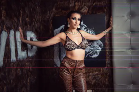 Glamorous woman in leopard print bikini and snakeskin pants posing against a wild animal print backdrop.