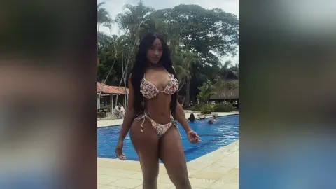NohomiCambel stands poolside in a patterned string bikini, showing off her long dark hair and toned body.