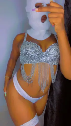 Woman in silver sequin bikini top and white briefs posing confidently in a glamorous outfit.
