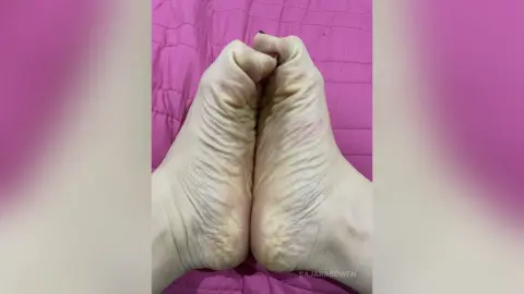 Close-up of bare feet resting on a soft pink textured fabric background in a relaxing mood.