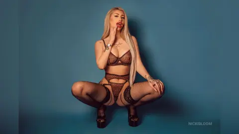 ViviAnne — NickiBloom poses in brown lace lingerie and fishnet stockings against a blue background.