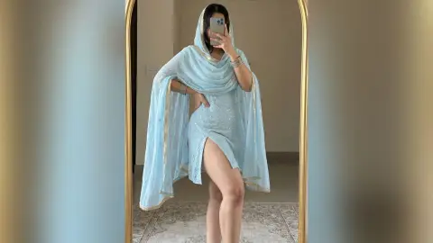 Woman in light blue traditional Indian salwar kameez outfit posing in a mirror for a graceful ethnic look.