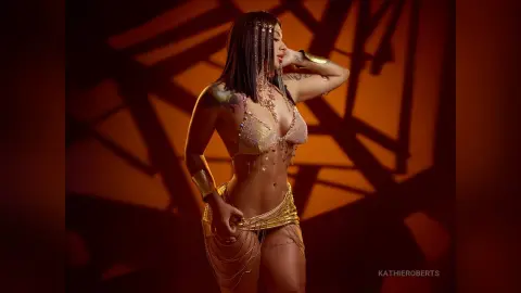Glamorous woman in a gold sequin bikini and beaded jewelry posing against a warm, dramatic shadow background.
