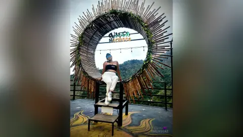 Woman in black crop top and white pants sitting under a circular bamboo structure at Vista Hermosa viewpoint.