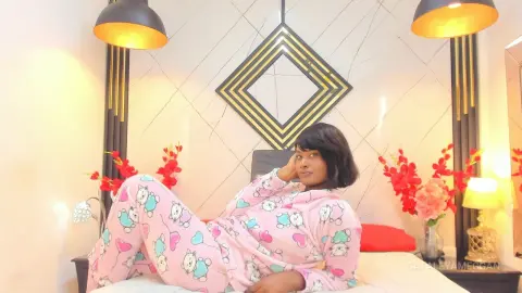 Young woman in pink animal print pajamas relaxing on a bed in a bright, modern bedroom.