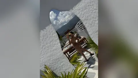 Slim woman in a bikini relaxing by a poolside lounge in a sunny tropical resort setting.