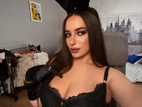 Glamorous woman in a black lace outfit and gloves posing in a cozy indoor setting.