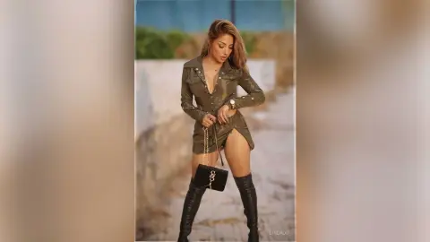 Stylish woman in an olive green mini dress and black boots posing outdoors in a chic, confident mood.