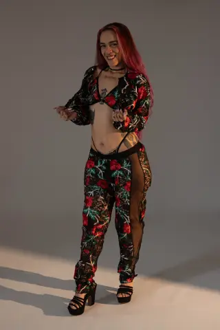 dannacastle19 smiles while wearing a black floral lace crop top and matching lace pants that show her stomach and hips.