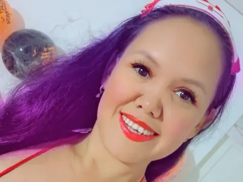 Smiling woman with long dark hair and red lipstick posing for a bright, cheerful selfie.