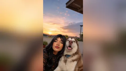 AnastasiaVelo — AnastasiaVelo smiles next to a large husky dog on a balcony during a golden sunset.