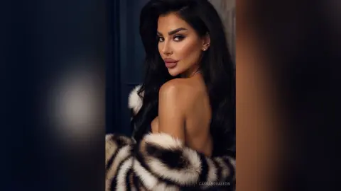 Glamorous woman with long dark hair wearing a luxurious faux fur wrap in a moody, elegant studio setting.
