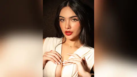 Glamorous woman in a white plunging neckline top with red lipstick posing against a dark background.