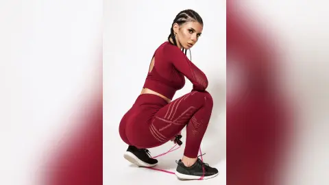 Athletic woman in maroon yoga set posing in a studio with a confident, sporty mood.