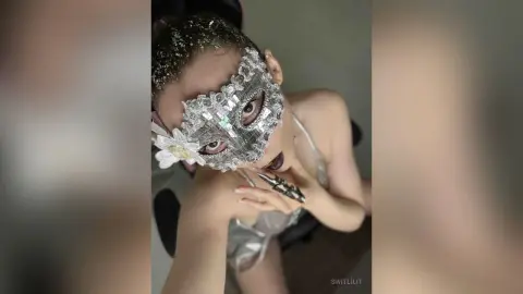 Glamorous woman in a sparkling silver sequin mask and white outfit posing with a mysterious, festive mood.