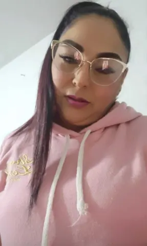 Woman with glasses wearing a cozy pink hoodie in a bright indoor setting.