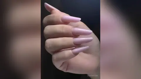 Close-up of long lavender almond-shaped acrylic nails on a hand against a dark background.