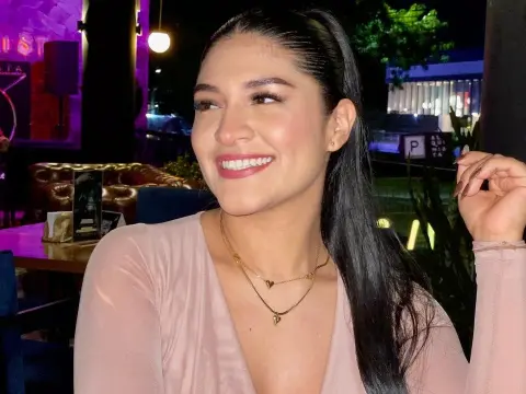 Smiling young woman in a pink long-sleeve top enjoying a night out at an outdoor restaurant terrace.