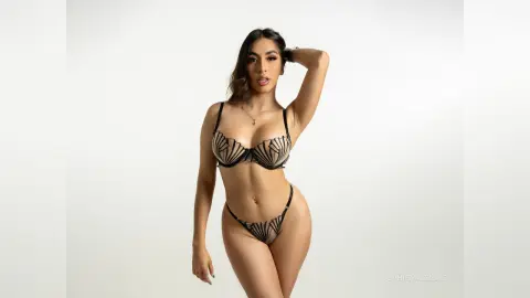 Confident woman in black patterned lingerie posing against a clean white studio background.