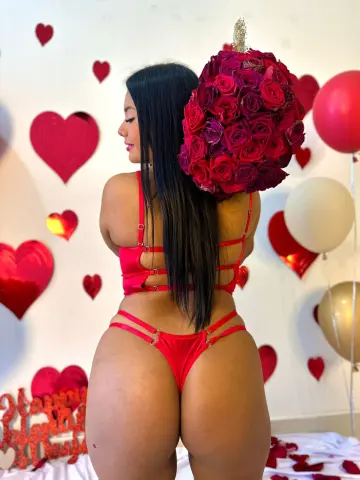 Curvy woman in red bikini posing against a romantic heart and rose balloon backdrop for a Valentine's Day theme.