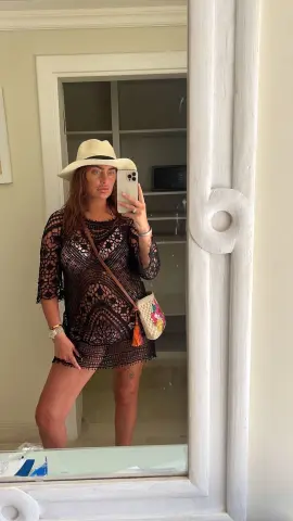 Bellamay95 poses for a mirror selfie wearing a black lace mini dress and a white sun hat while holding a phone.