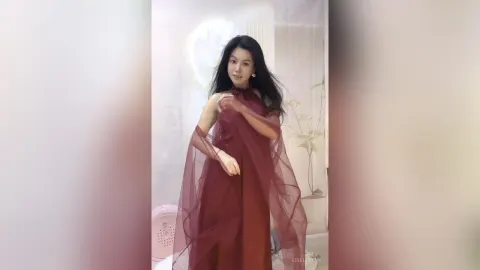 KireliaYan — KireliaYan poses in a flowing maroon sheer dress with her long black hair down.