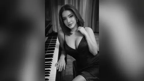 Elegant woman in a black satin slip dress posing by a piano in a moody, cinematic black and white setting.