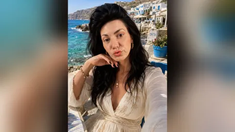 SofiaBleir — SofiaBleir wears a white dress and gold jewelry while posing outdoors by the blue ocean.
