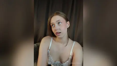 EvelinaMoorina looks at the camera with her tongue out while wearing a white lace bra.