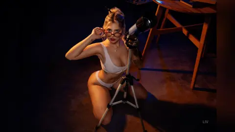 Blonde woman in white lingerie posing in a dark studio with professional photography lighting equipment.