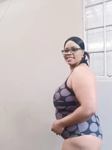 Smiling woman in a polka dot swimsuit posing in a bright indoor setting.