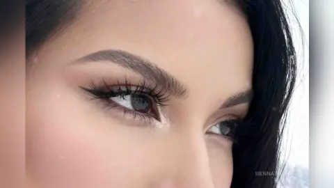 Close-up of a woman with glamorous winged eyeliner, long lashes, and groomed eyebrows for a beauty look.
