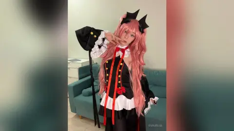 Cosplayer in pink wig and black gothic maid outfit posing in a living room.