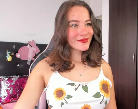 LunaGrealish smiles while wearing a white sunflower print tank top with her brown hair styled in waves.