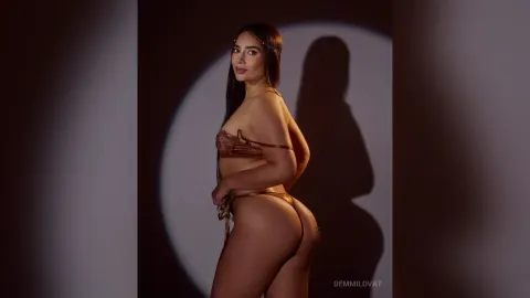 DemmiLovat — DemmiLovat poses in bronze lace lingerie against a dark background with a spotlight shadow.