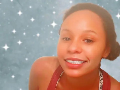 Smiling young woman in a red top against a dreamy blue starry background.