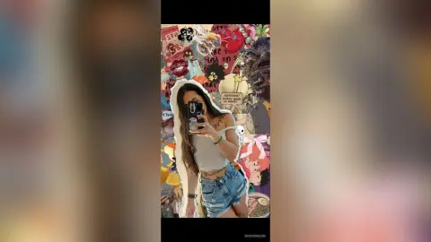 Young woman in a white tank top and denim shorts taking a mirror selfie in a colorful, collage-style room.