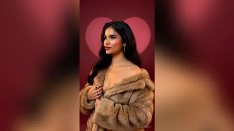 Elegant woman in a luxurious brown faux fur coat posing against a romantic red heart background.