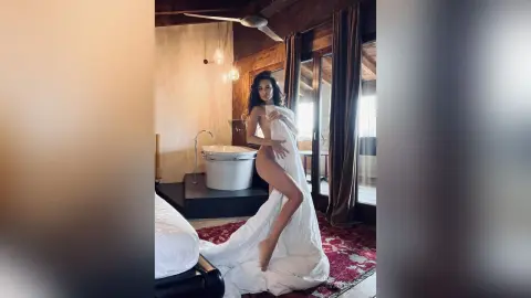 Elegant woman wrapped in a white sheet relaxing in a luxury modern bathroom with a freestanding tub.